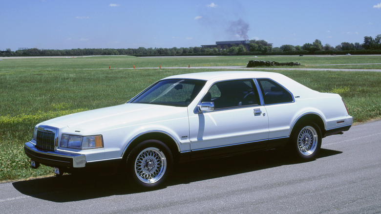 White Lincoln Mark VII LSC parked in front of grassy field.