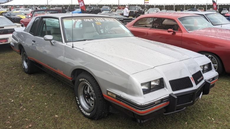 Silver 1986 Pontiac Grand Prix 2+2 on display at a Mecum auction.