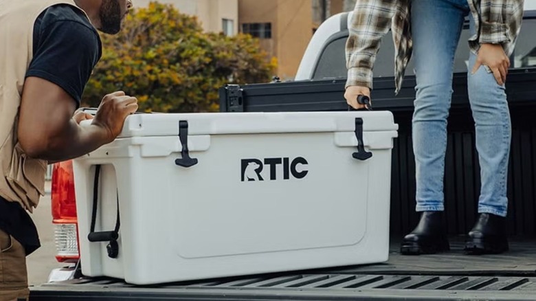 white rtic cooler being loaded into truck bed
