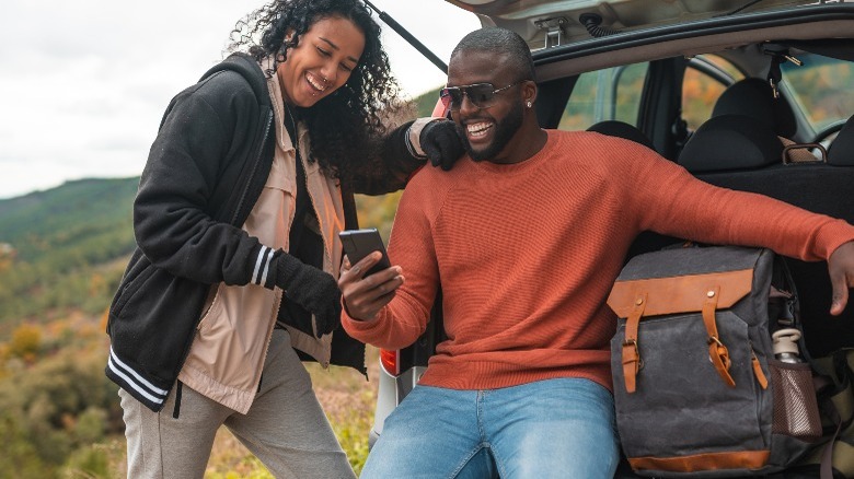 Two people on phone with car trunk open