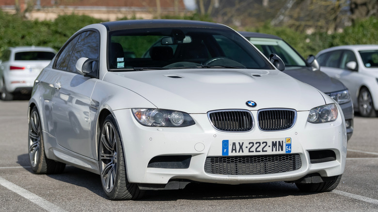 A white BMW E92 M3 parked in a public car park.