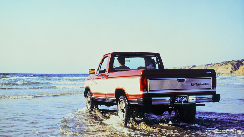 1985 Ford Ranger Base driving through shallow water on tidal beach, rear-left 3/4 view