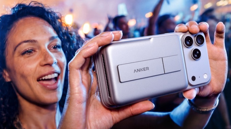 Woman holding up an iPhone with an Anker MagGo Power Bank 2 Pro attached