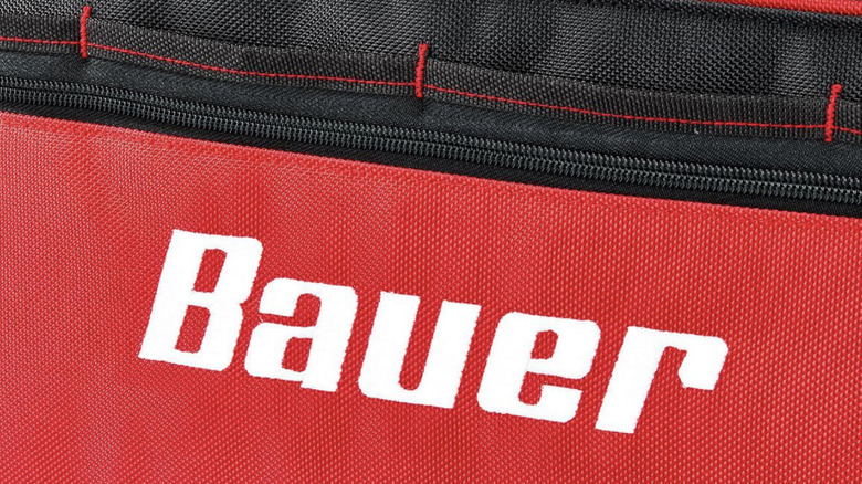 A close-up of a white Bauer logo on a red and black tool bag