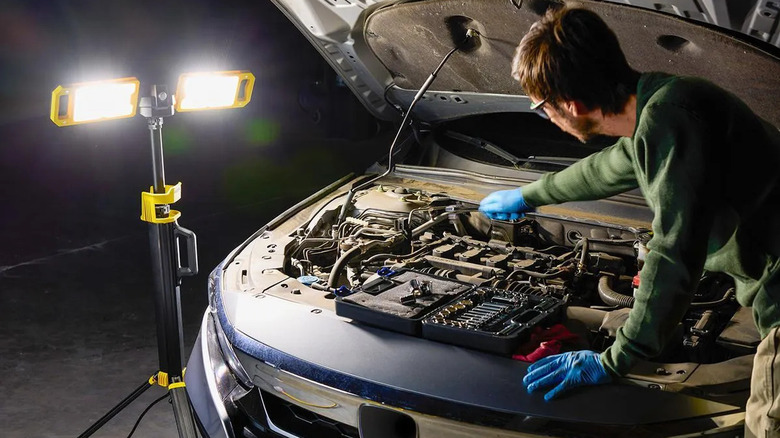 guy fixing car with worklight