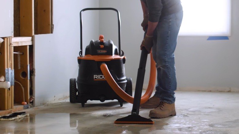 A person using a Ridgid vacuum on the floor.
