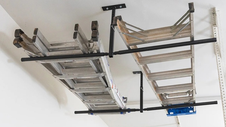 Two ladders stored in a ceiling rack.