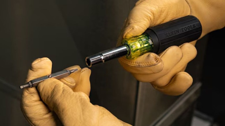 A person swapping out a screwdriver's interchangeable blade