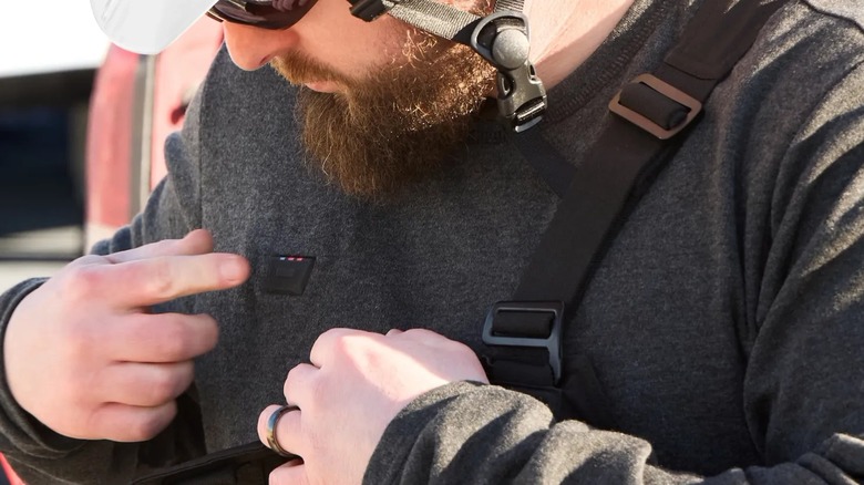 A man turning on a Milwaukee heated baselayer shirt.