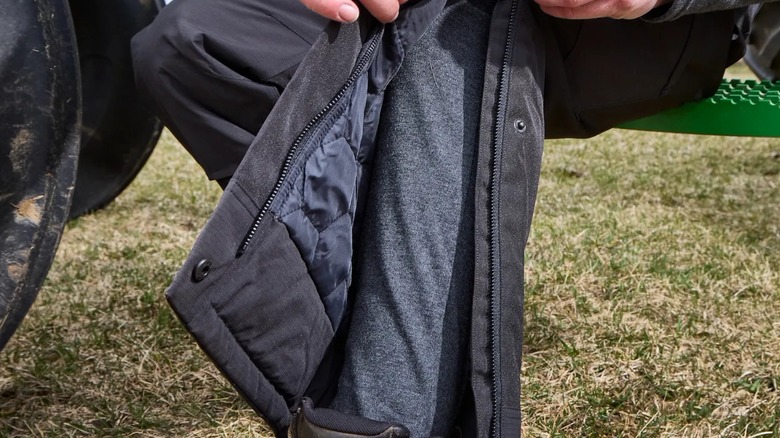 A person showing their Milwaukee baselayer pants under their work pants.