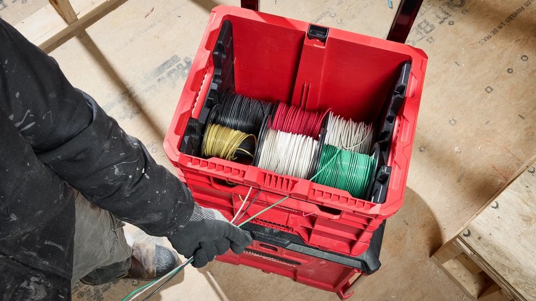 A person pulling wire from a Milwaukee Packout Wire Pulling XL Crate