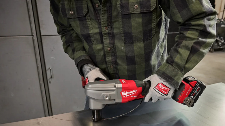 person cutting a semicircle out of sheet metal with a nibbler tool