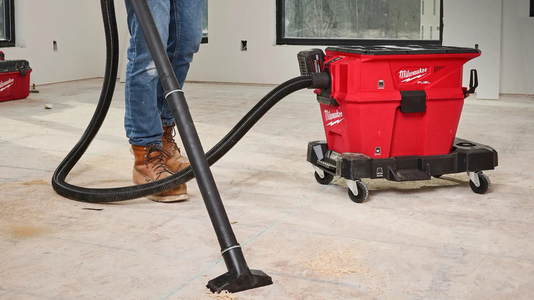 person vacuuming up sawdust
