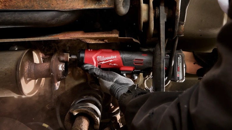 A person using a Milwaukee die grinder on metal.
