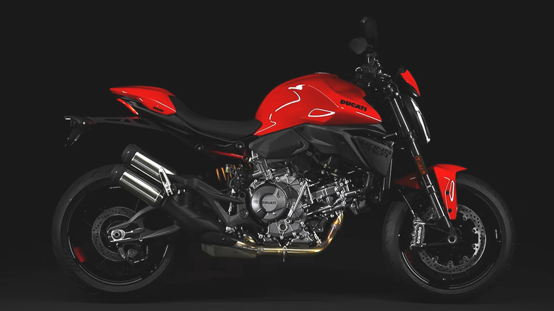 An image of red-and-black Ducati Monster+ is displayed against a simple black backdrop.