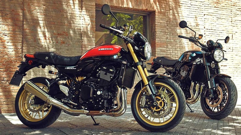 A photo of two black Kawasaki Z900RS models parked in front of a brick wall.