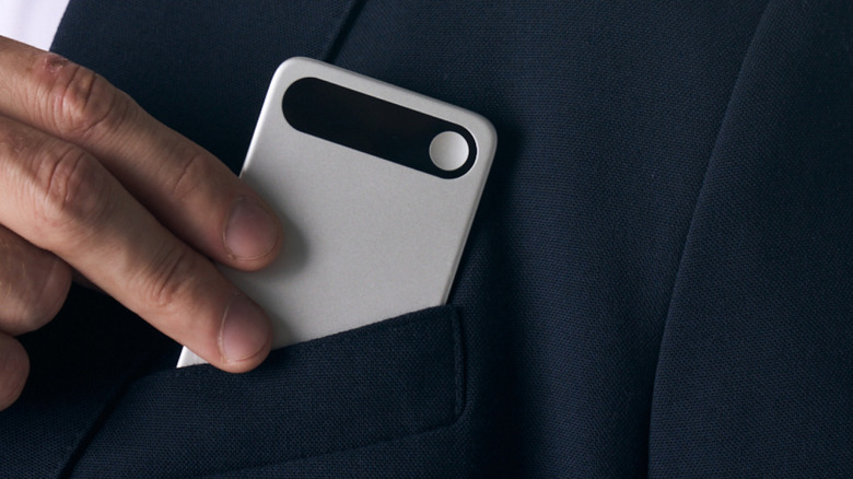 Man placing a silver device in a front suit jacket pocket.