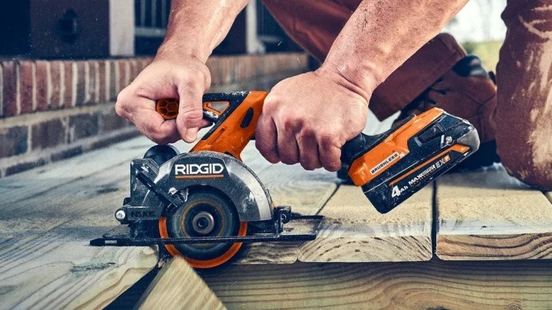 Ridgid NUKE subcompact circular saw being used to cut through wooden floorboards.