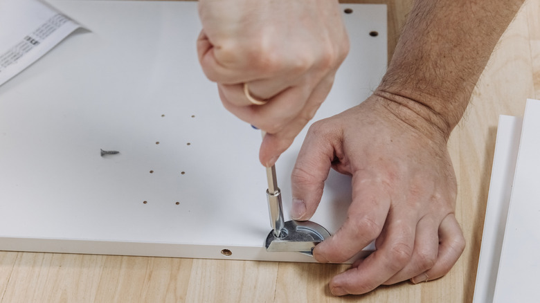 Close-up shot of a man's hands using a manual screwdriver to install hardware