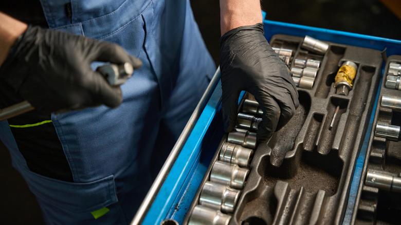 Mechanic places tools in a tool drawer.