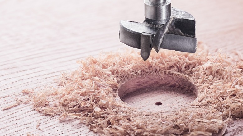 a Forstner bit showing the hole it made with a flat bottom