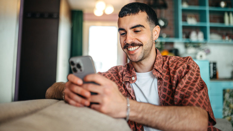 A person smiling while using their smartphone.