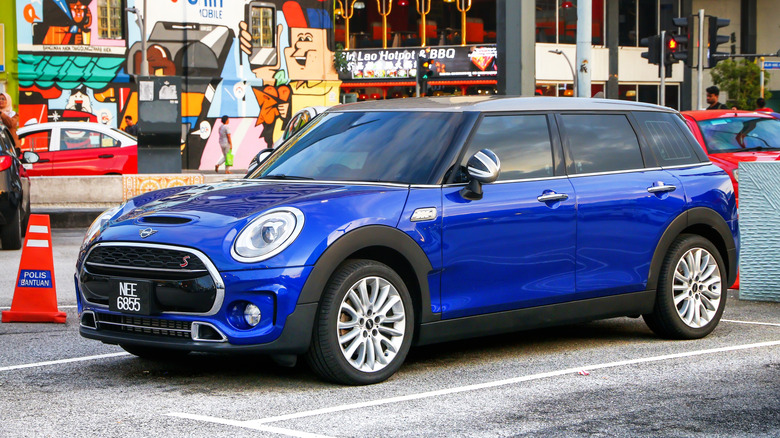 A blue Mini Clubman parked on an urban parking lot.