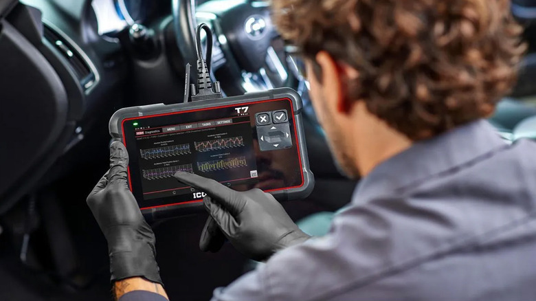 A mechanic using an ODBII scanner on a vehicle