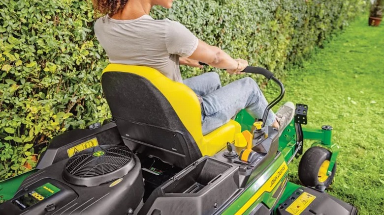 Woman mowing lawn with John Deere zero-turn mower