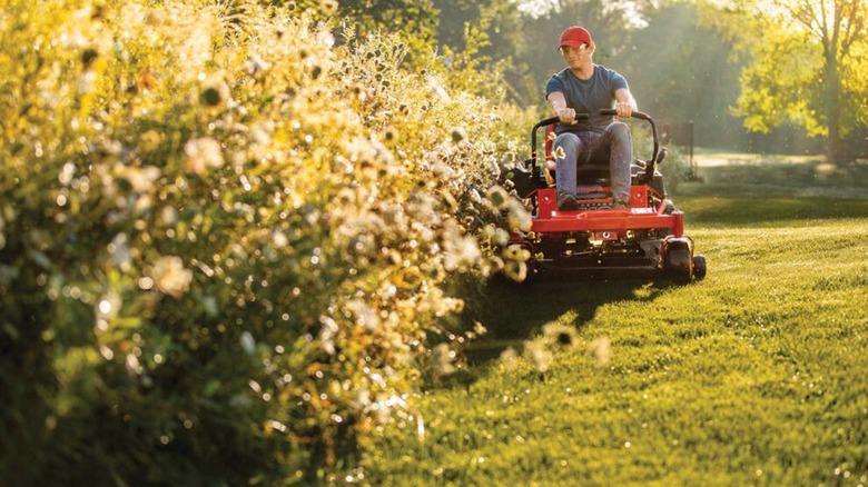 Person mowing lawn with Troy-Bilt zero-turn mower