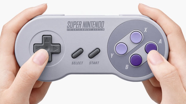 A person holding a wireless version of the Super Nintendo controller