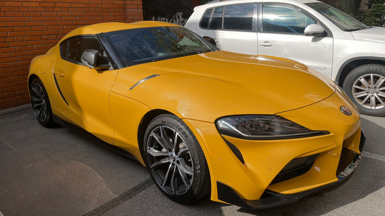 Yellow sport car Toyota Supra GR V (A90, A91) MK 5 in a parking lot on street.