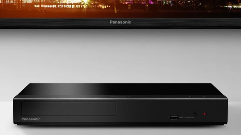 Panasonic DP-UB450P-K Blu-ray player on a white shelf below a Panasonic TV