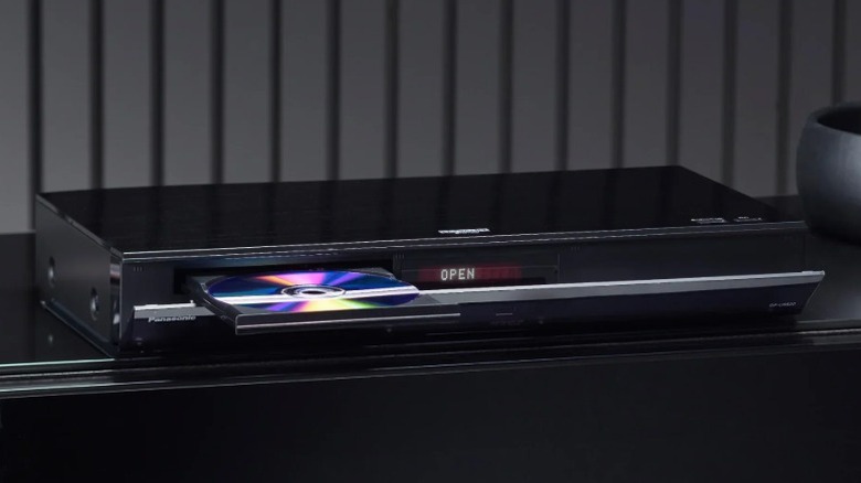 Panasonic DP-UB820-K Blu-ray player with disc tray open on a black shelf