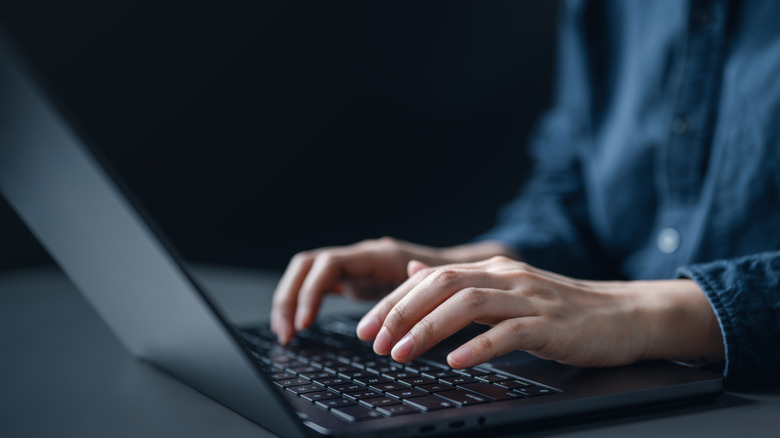 A person typing on a laptop at a desk