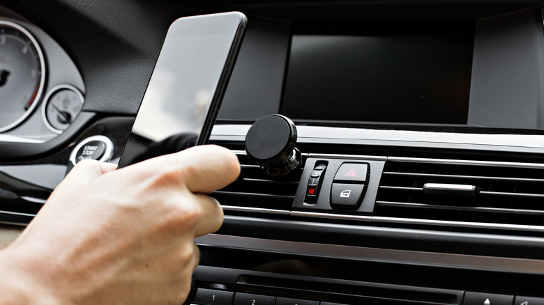 hand placing phone on phone mount in car