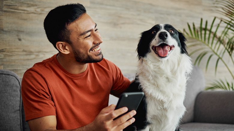 man holding phone with dog