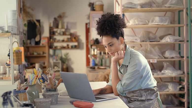 woman with laptop in pottery studio