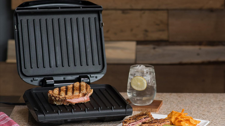 A George Foreman Grill cooking a sandwich on a counter