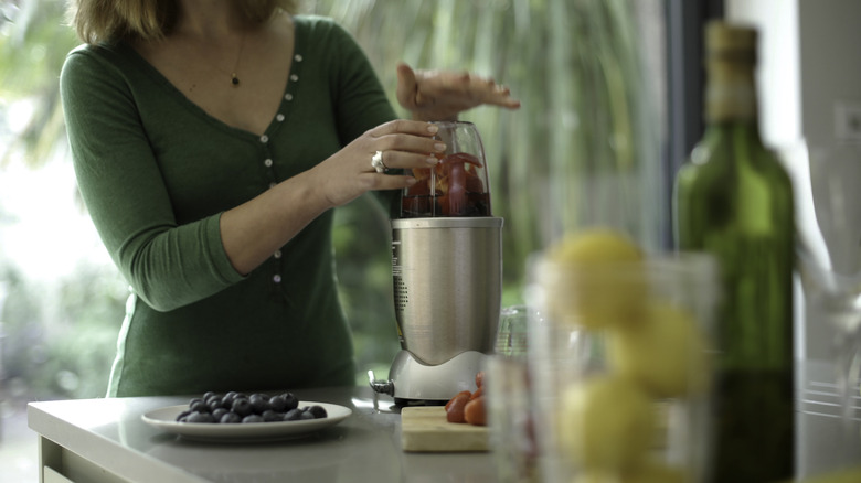 A woman mixing a smoothie in a single serve blender