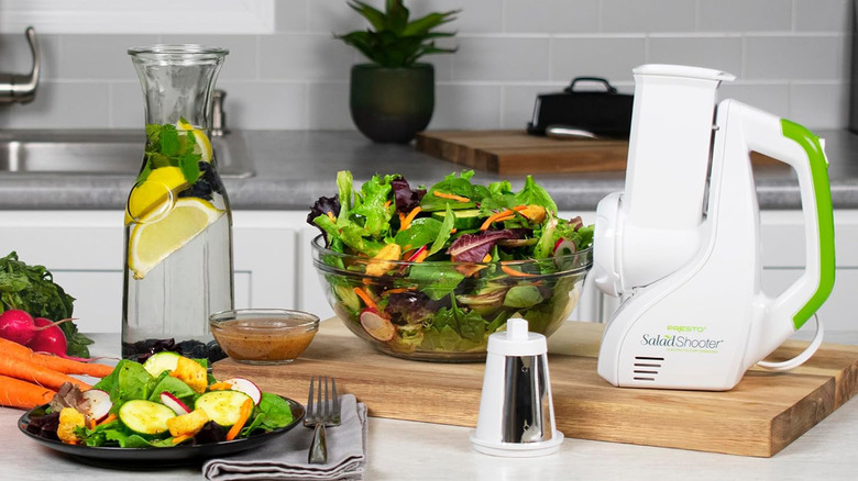 A Presto Salad Shooter next to a big bowl of salad on a counter