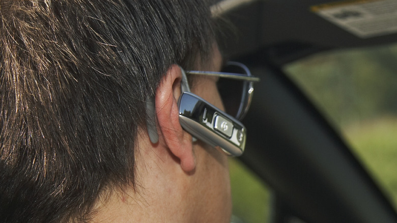 man driving and wearing earbud 