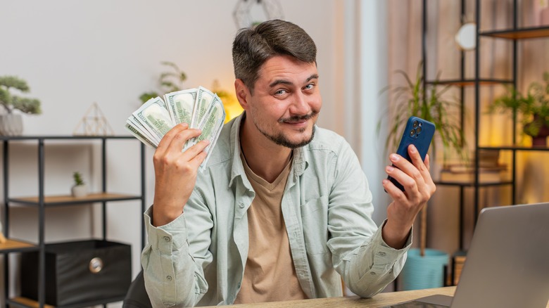 Man holding iPhone and cash in hands