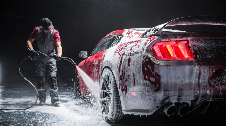Man rinsing foam-covered car