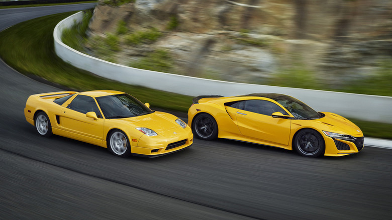 Two yellow Acura NSX's side by side on a winding road.