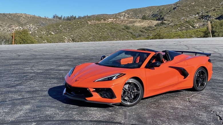An orange Chevy Corvette with the top removed parked, mountains in the background.
