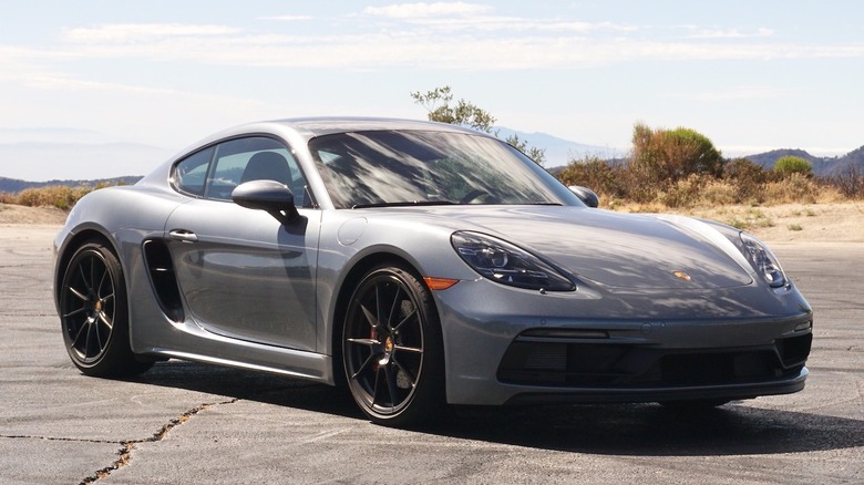 Porsche Cayman GTS 4.0 parked in the mountains in front of trees and bushes.