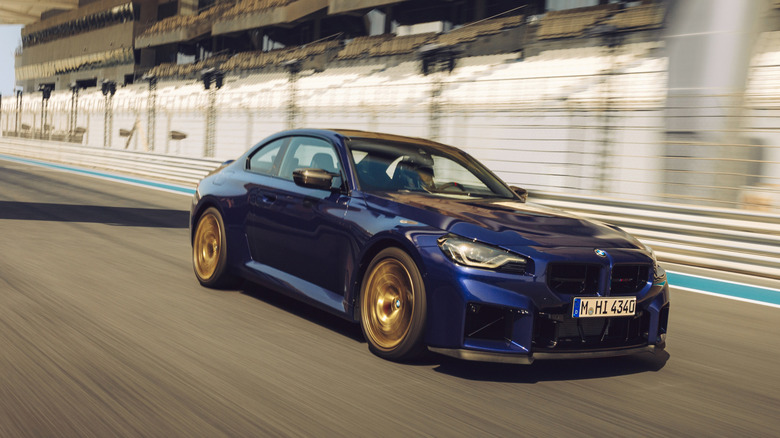 2026 BMW M2 CS driving down racetrack at speed, front-right 3/4 view