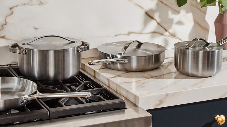 Caraway Stainless Steel Cookware set on gas stove and faux marble countertop