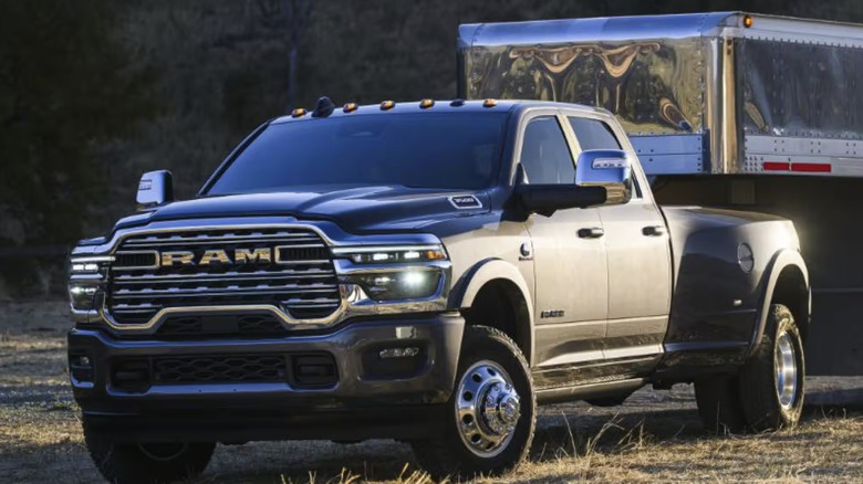 A black Ram 3500 dually truck towing trailer on grass